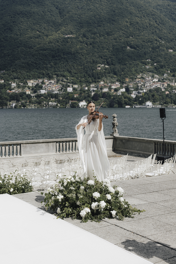 The bride stands at the flower-lined ceremony space overlooking Lake Como at Villa Pizzo.