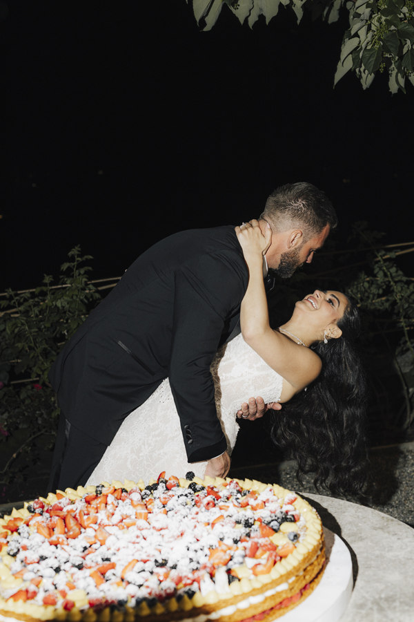 The groom dips the bride beside a large fruit tart at Villa Pizzo.