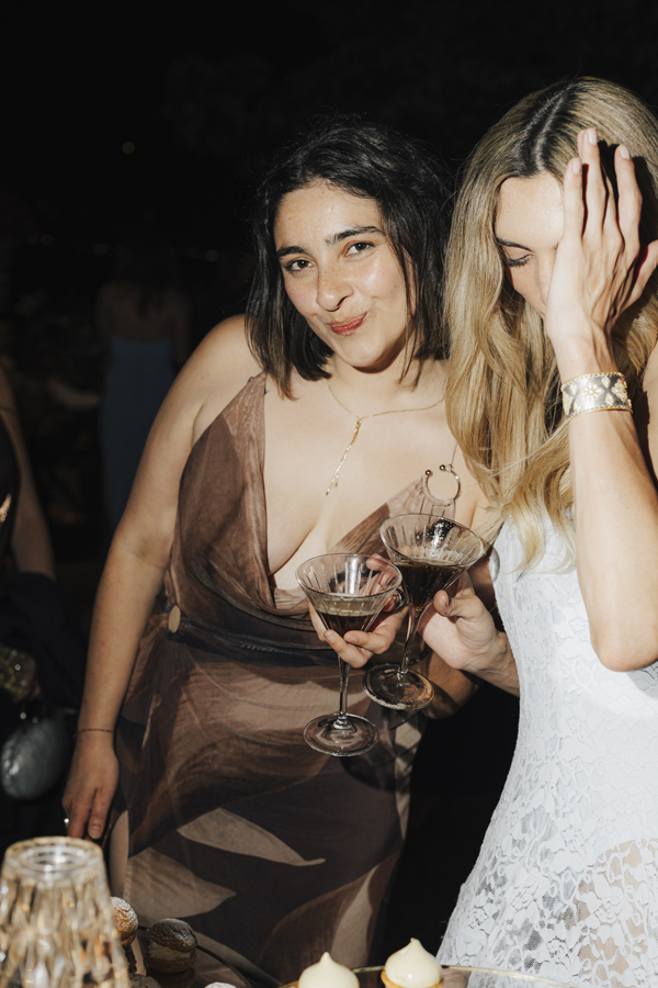 Two friends pose together with drinks at the Villa Pizzo evening party.