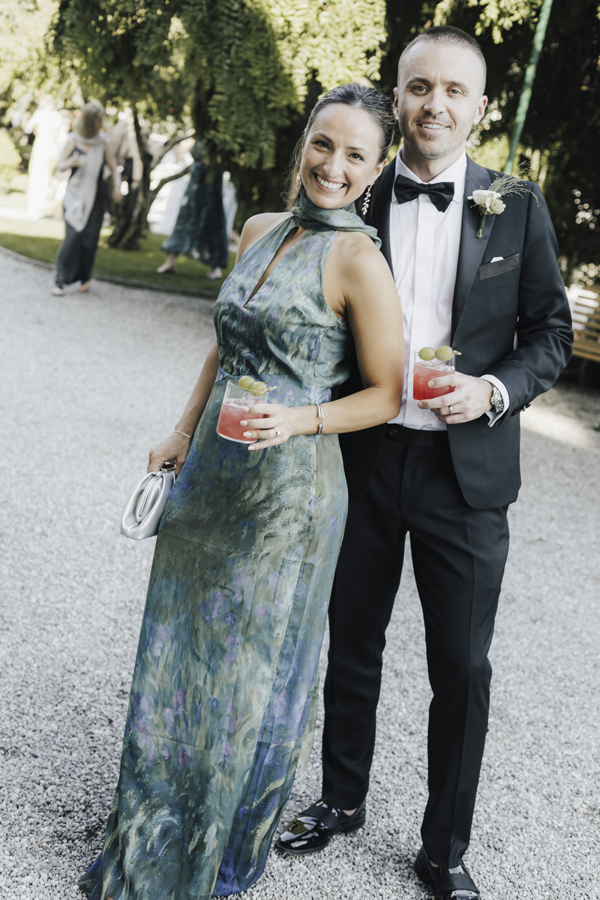 A couple pose together with drinks in the gardens of Villa Pizzo.