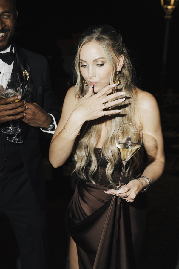 A guest in a dark dress holds a wine glass during the late-night celebration.