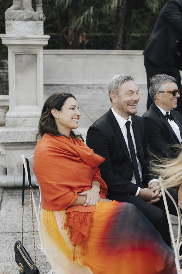 Guests watch the ceremony at Villa Pizzo, including a woman wrapped in bright orange.