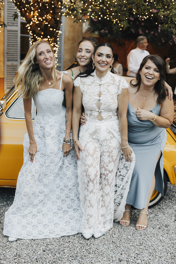 The bride poses with three friends beside the yellow car at Villa Regina Teodolinda.