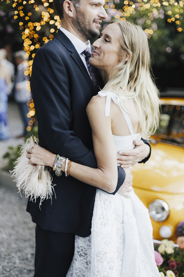 A couple embrace in the garden near the yellow car at Villa Regina Teodolinda.