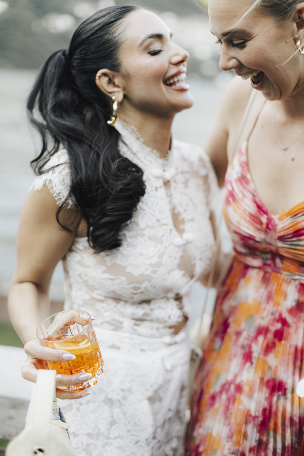 Close-up of a guest's feather clutch and jewellery beside a dark suit.