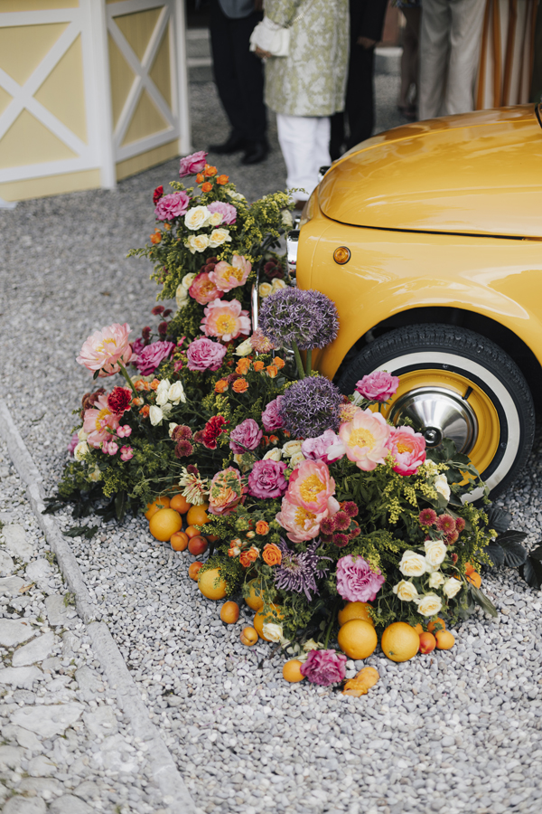 Colourful flowers and oranges arranged beside a yellow car at Villa Regina Teodolinda.