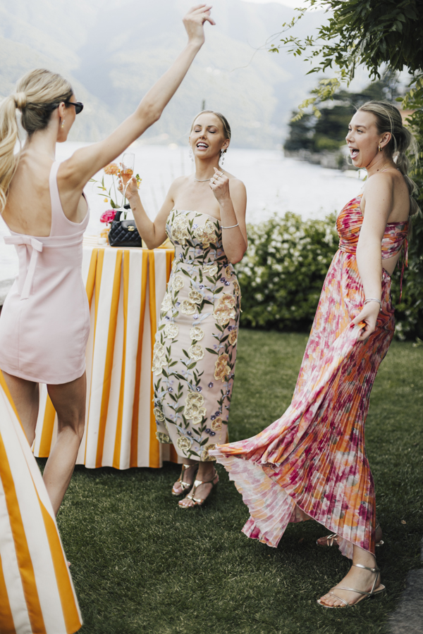 Three women dance together in the lakeside garden at Villa Regina Teodolinda.