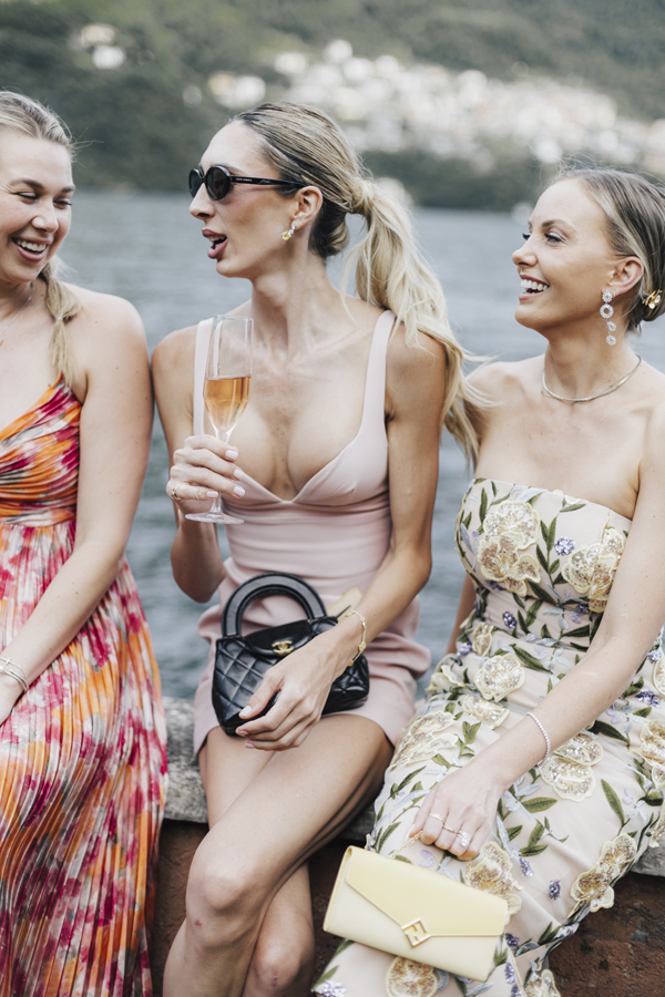 Three women sit together by the lake during the Villa Regina Teodolinda celebration.