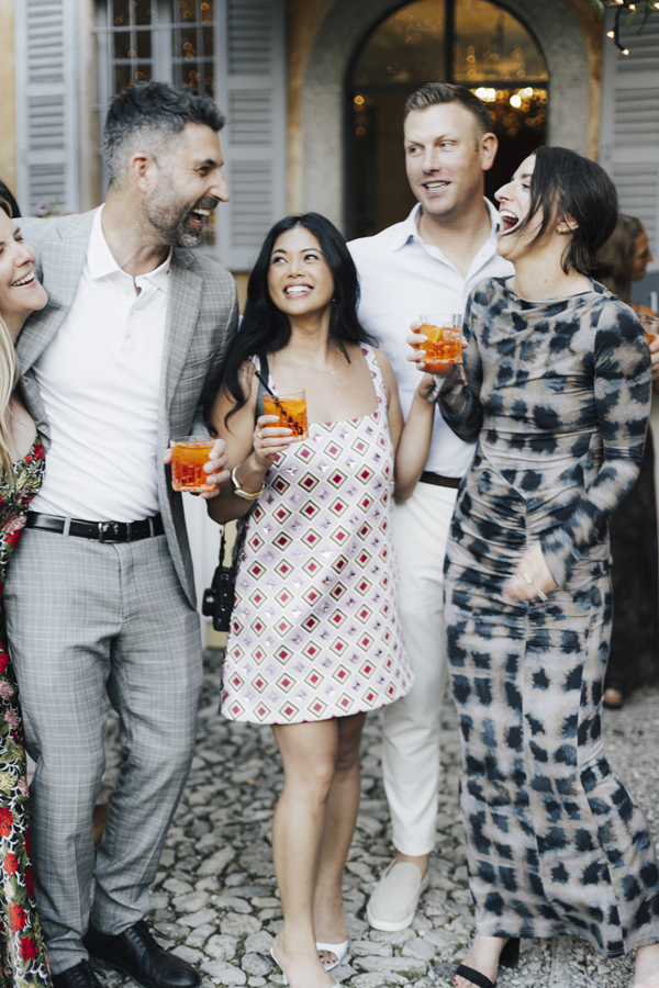 Four guests pose together with aperitivo drinks outside Villa Regina Teodolinda.