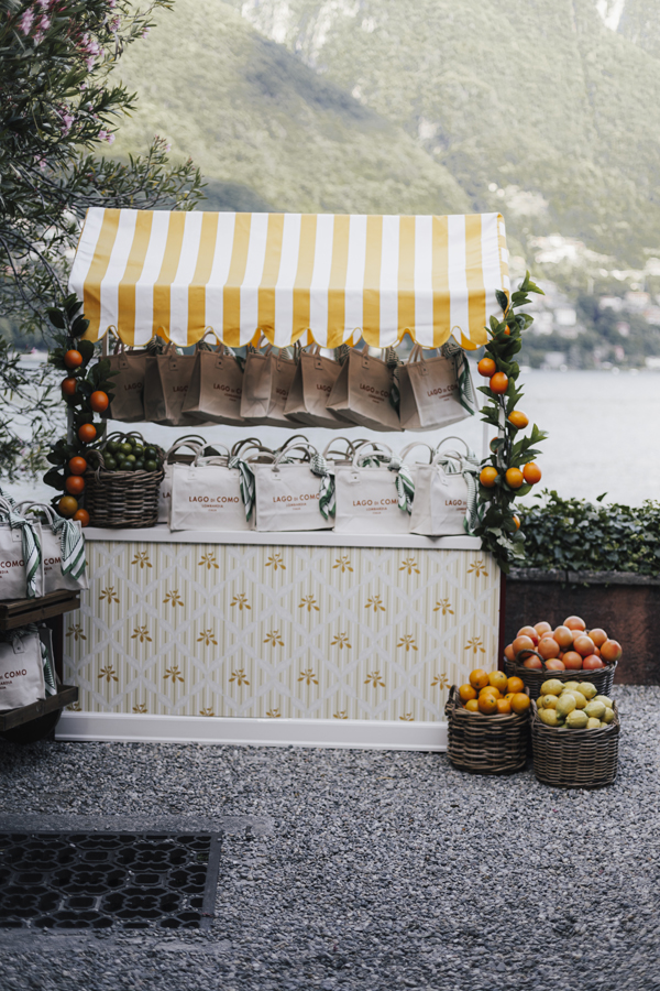A striped food cart decorated with citrus fruit beside Lake Como at Villa Regina Teodolinda.