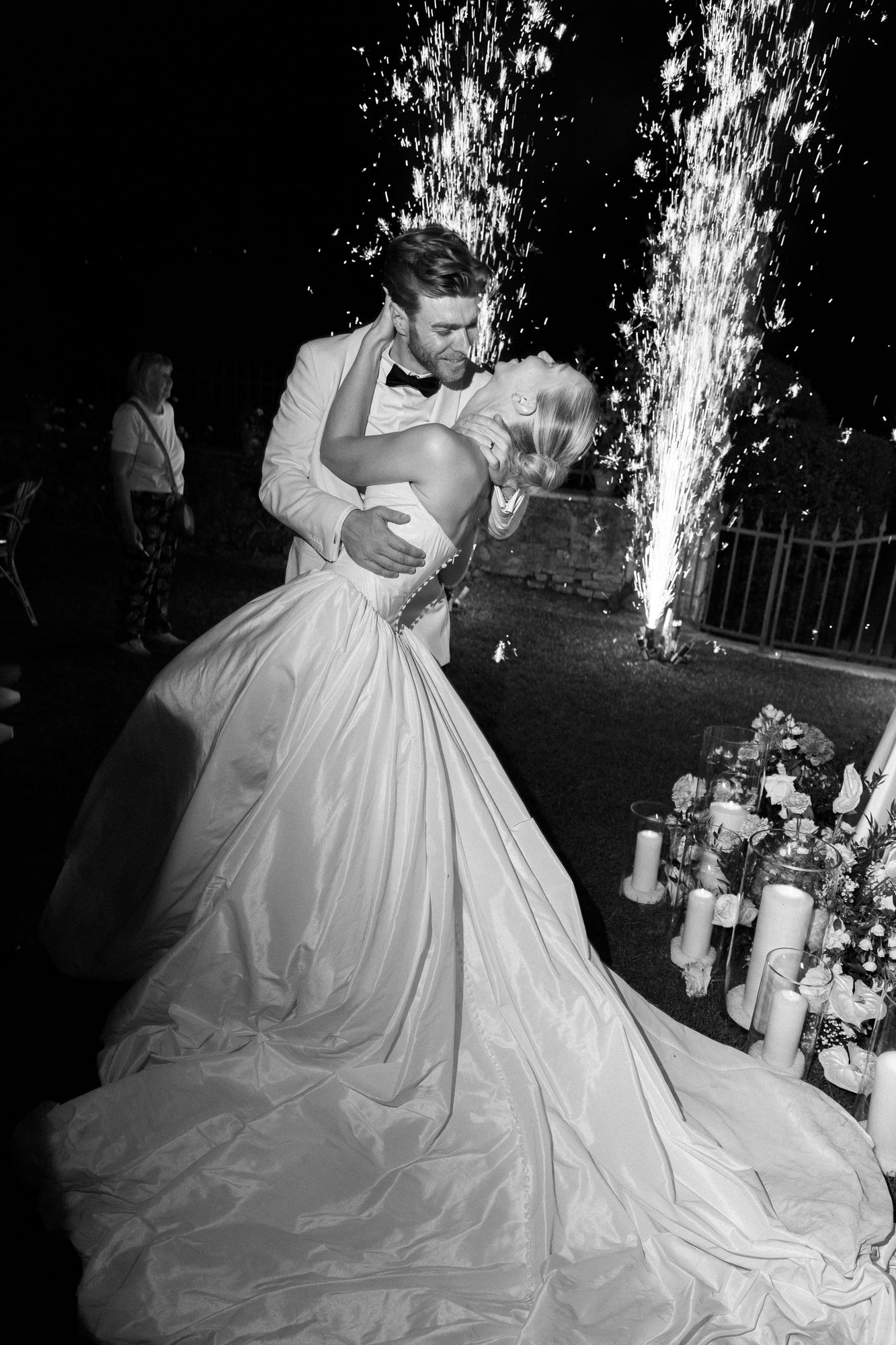 Couple embracing beneath fireworks after dark