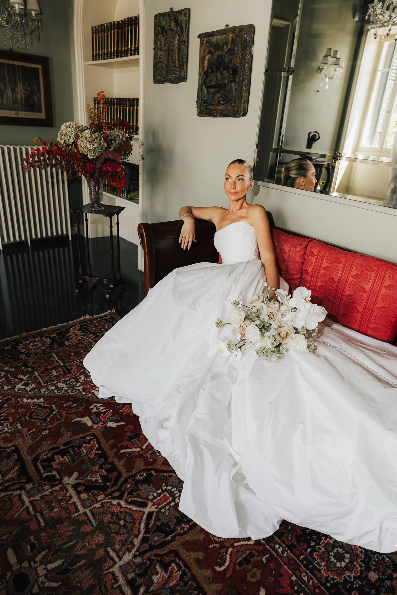 The bride seated on a red sofa before the ceremony