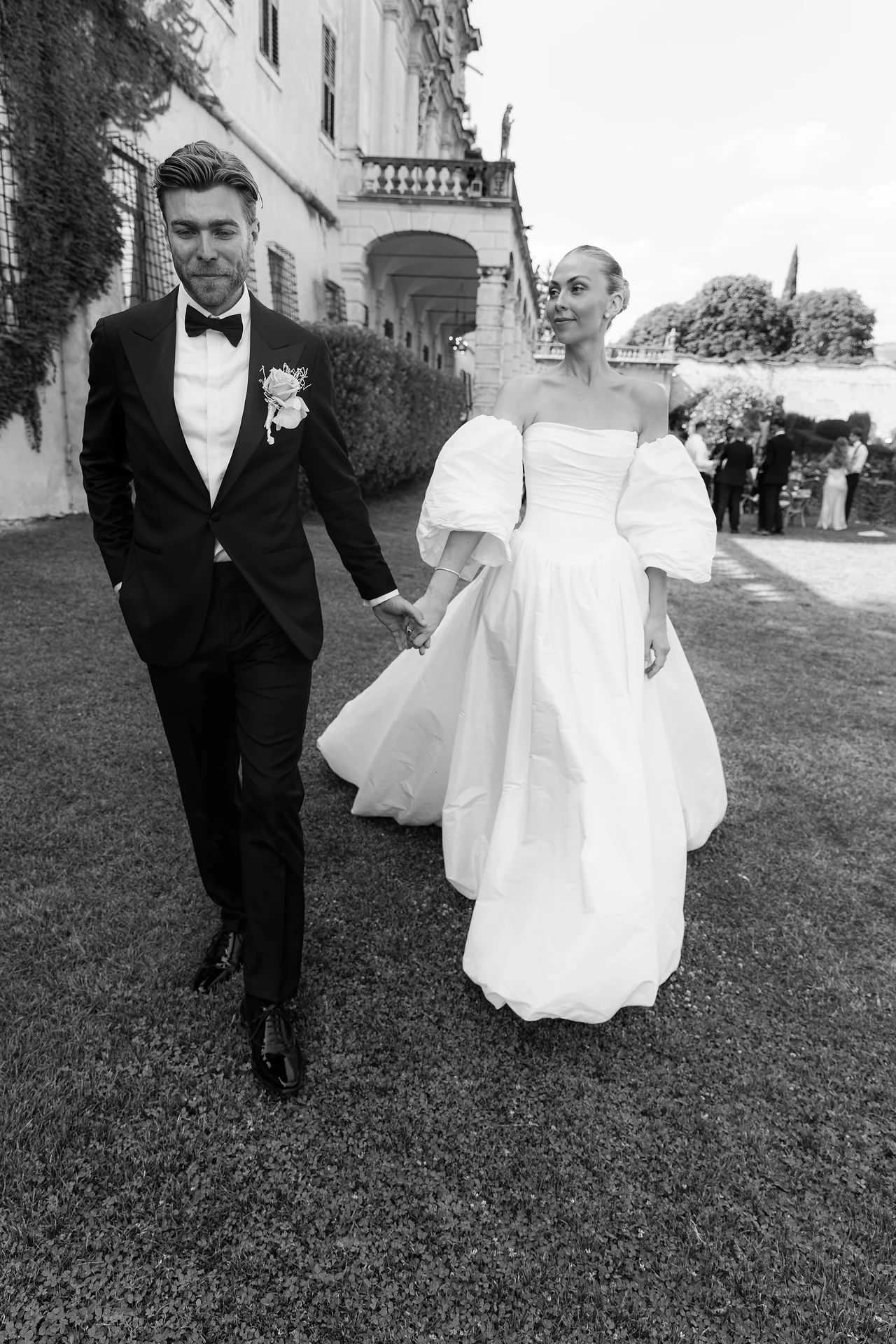 The newlyweds walking through the Villa Arvedi grounds in black and white