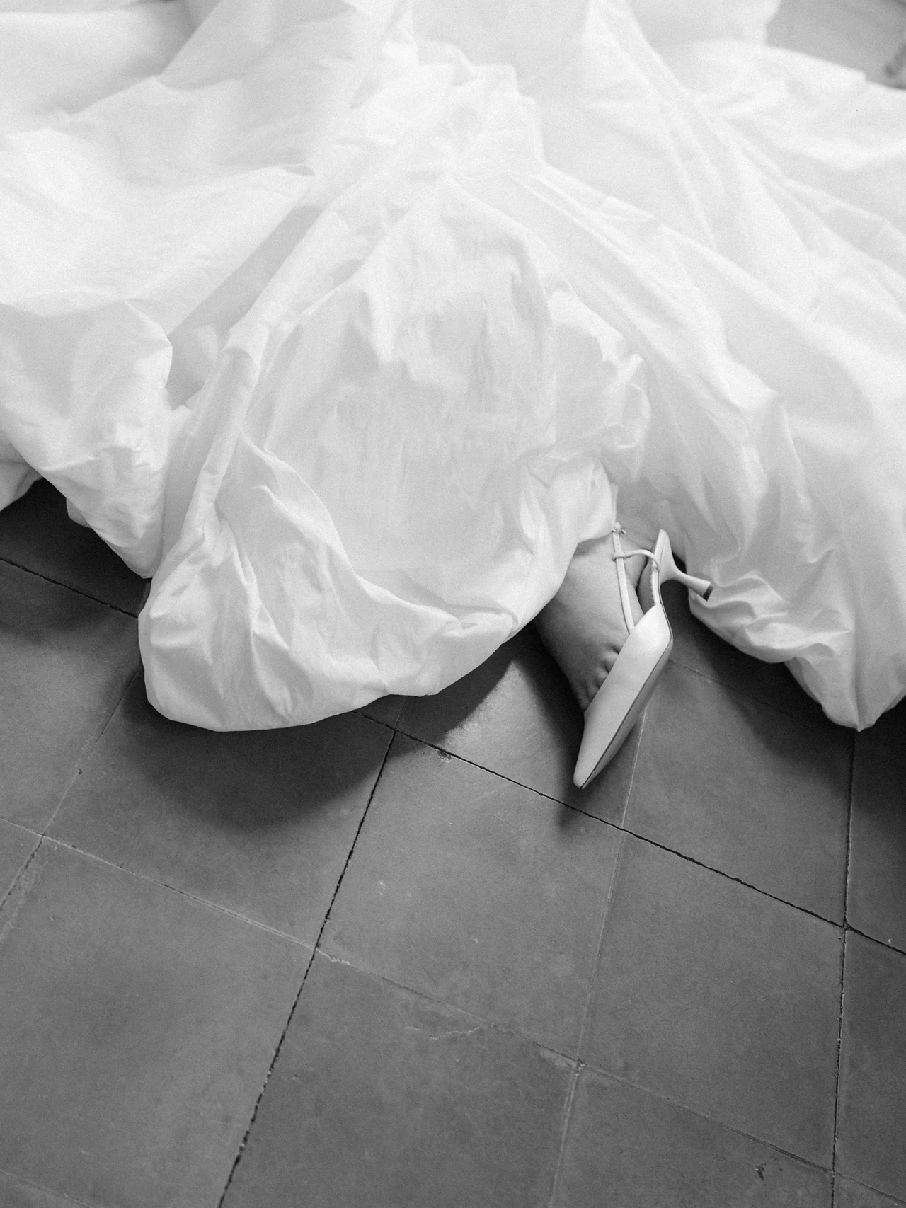The hem of the wedding dress and bridal heels