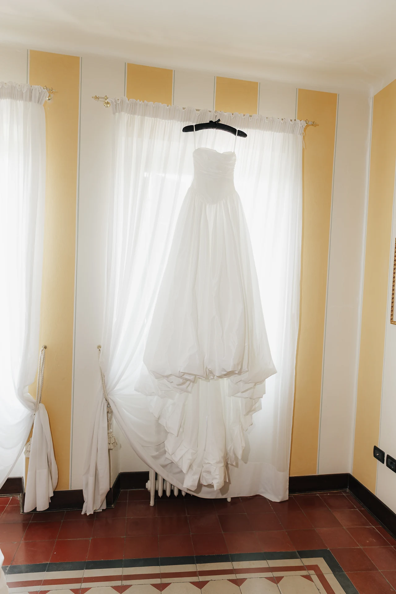 The wedding dress hanging in a sunlit room at Villa Arvedi
