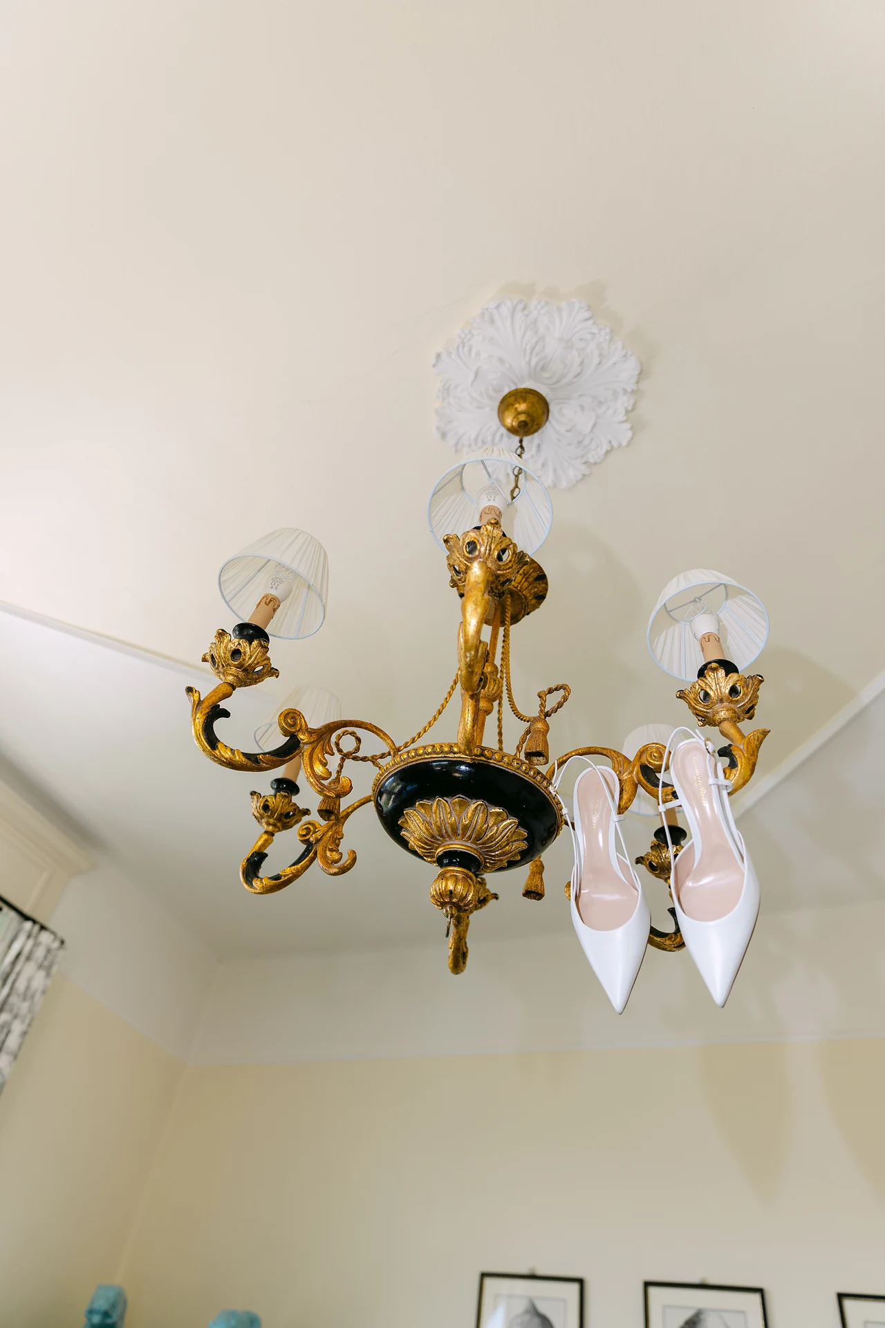 Bridal shoes suspended beneath an antique chandelier