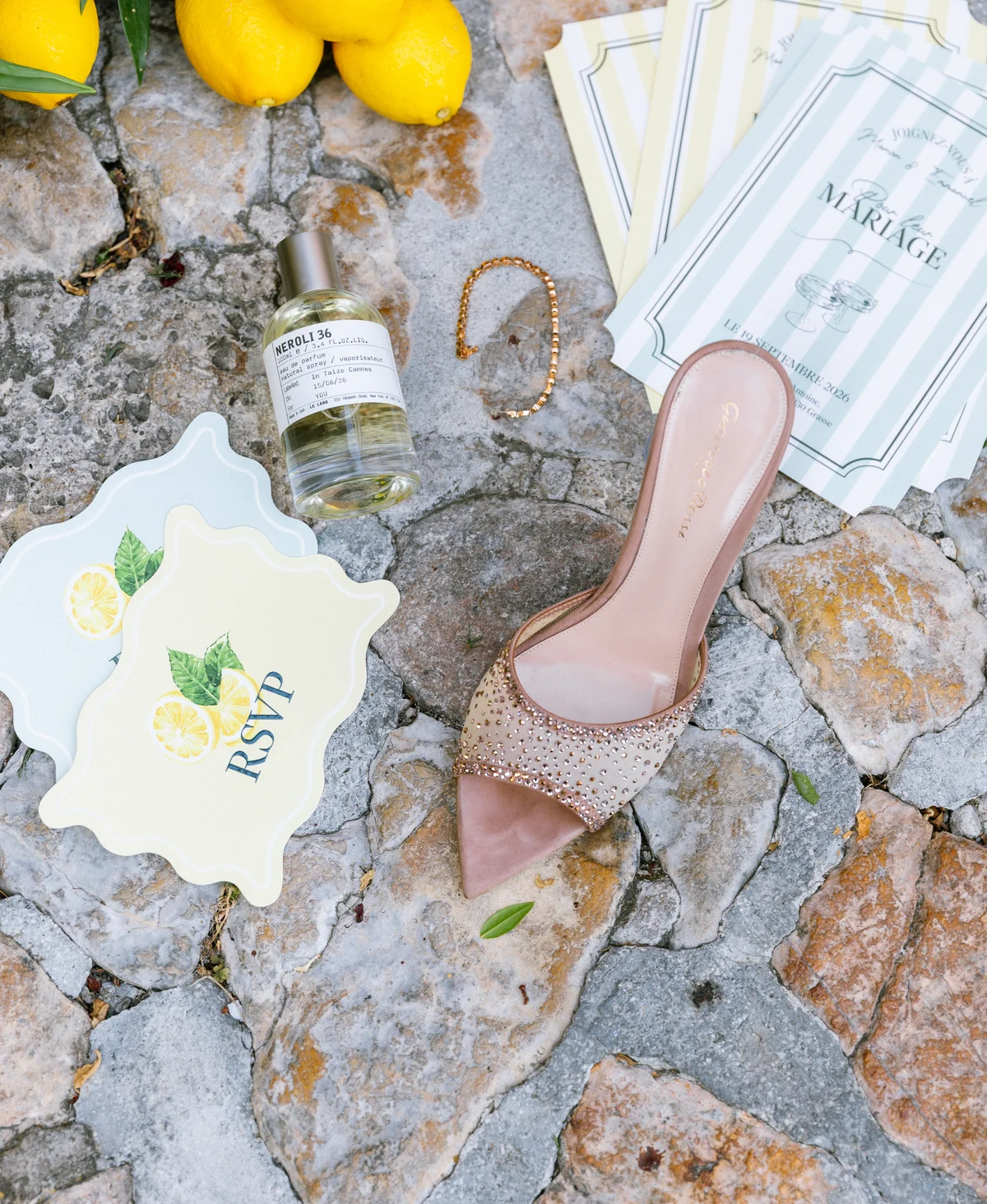 Lemons, wedding stationery and a pink designer shoe on stone