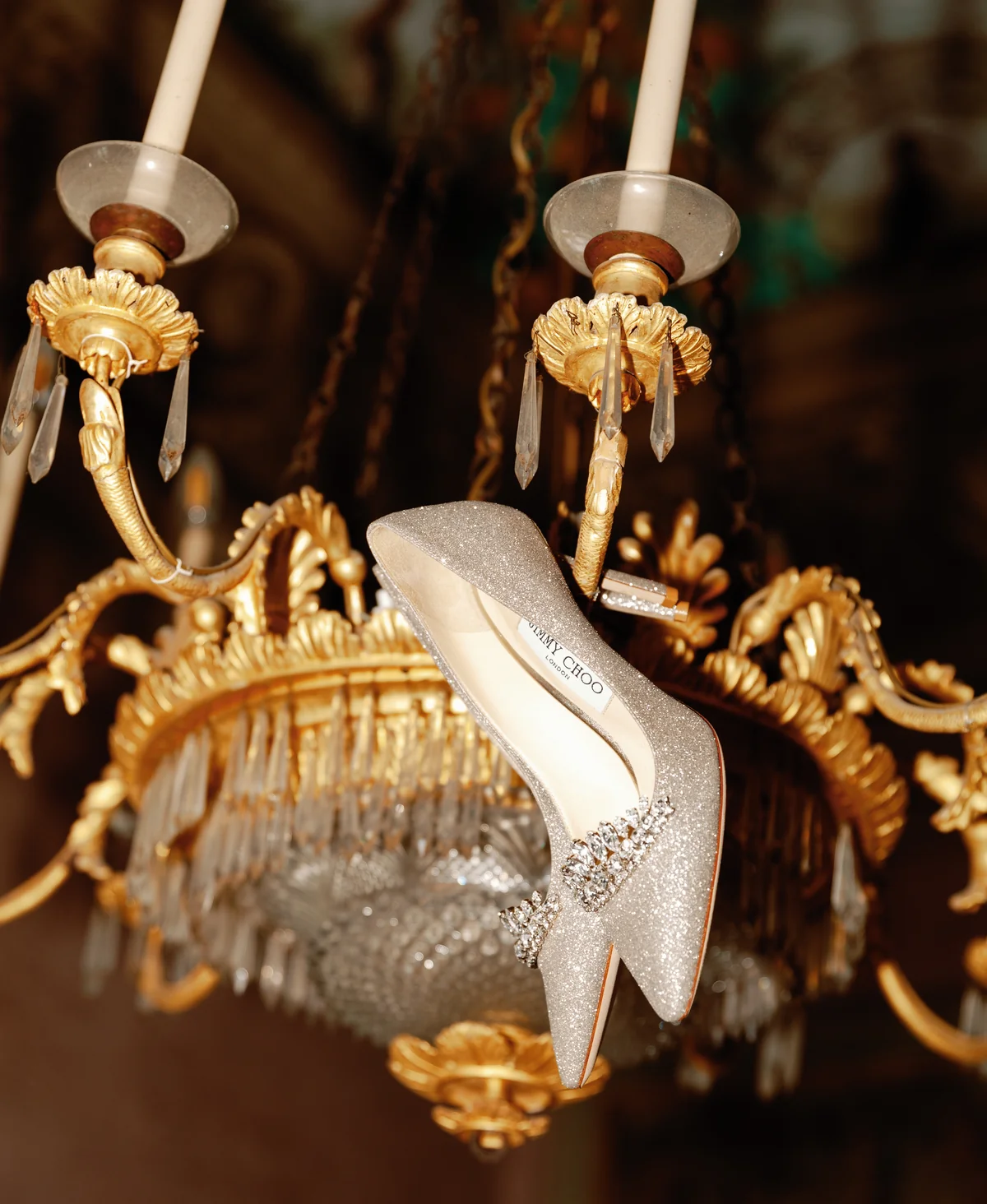 Sparkling bridal shoe suspended from an antique chandelier