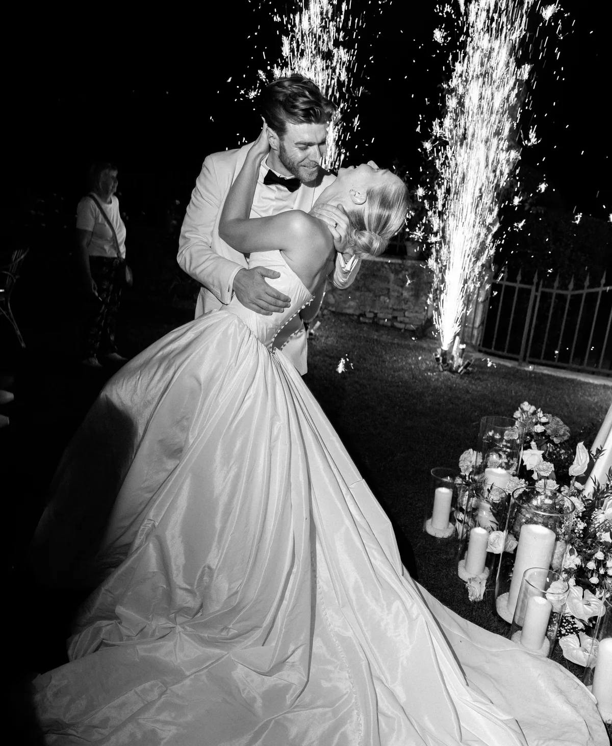 Newlyweds embracing beneath fireworks after dark