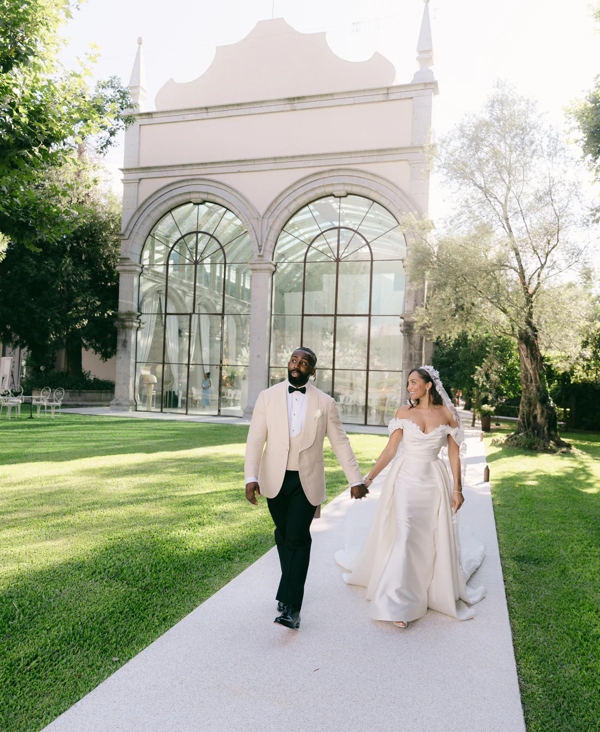 Newlyweds walking beside the glass pavilion at Solar da Levada