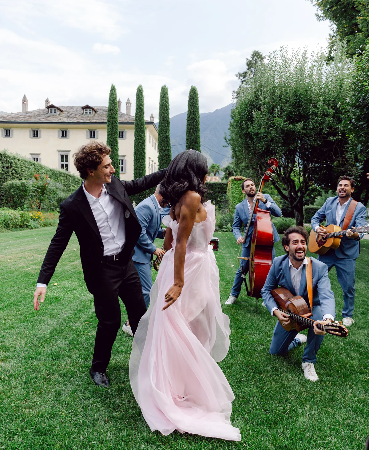 A couple dancing with live musicians in the gardens of Villa Balbiano