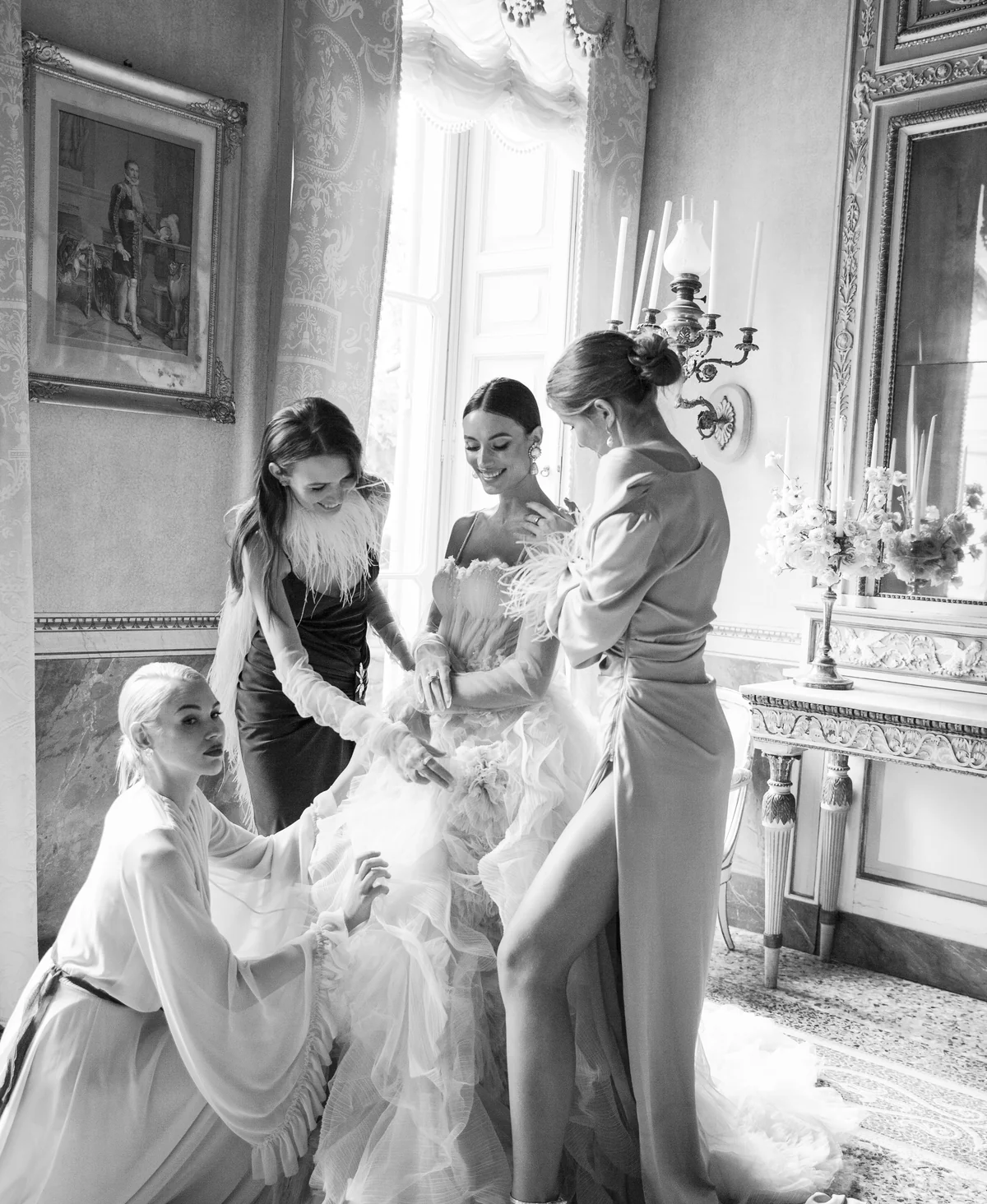 Bride surrounded by friends as they help with her gown