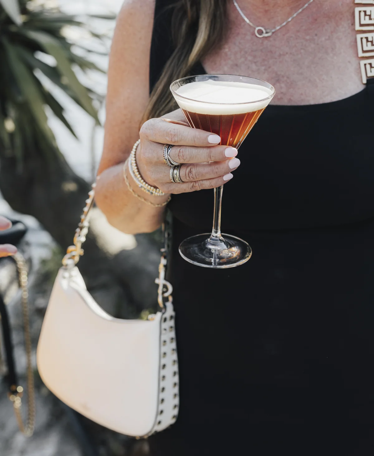 Wedding guest holding a cocktail in the afternoon light
