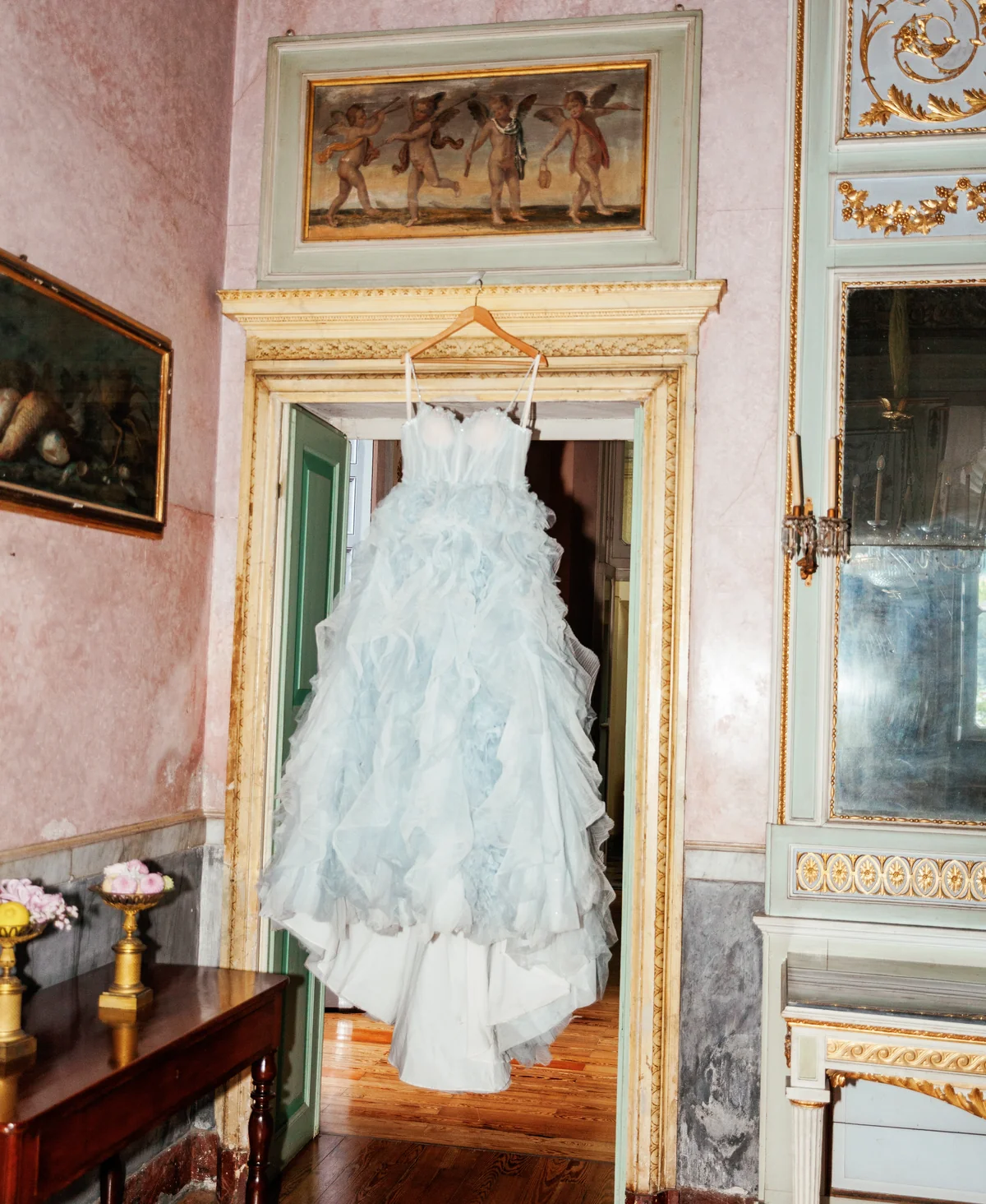 Pale blue wedding gown hanging in a gilded Italian room