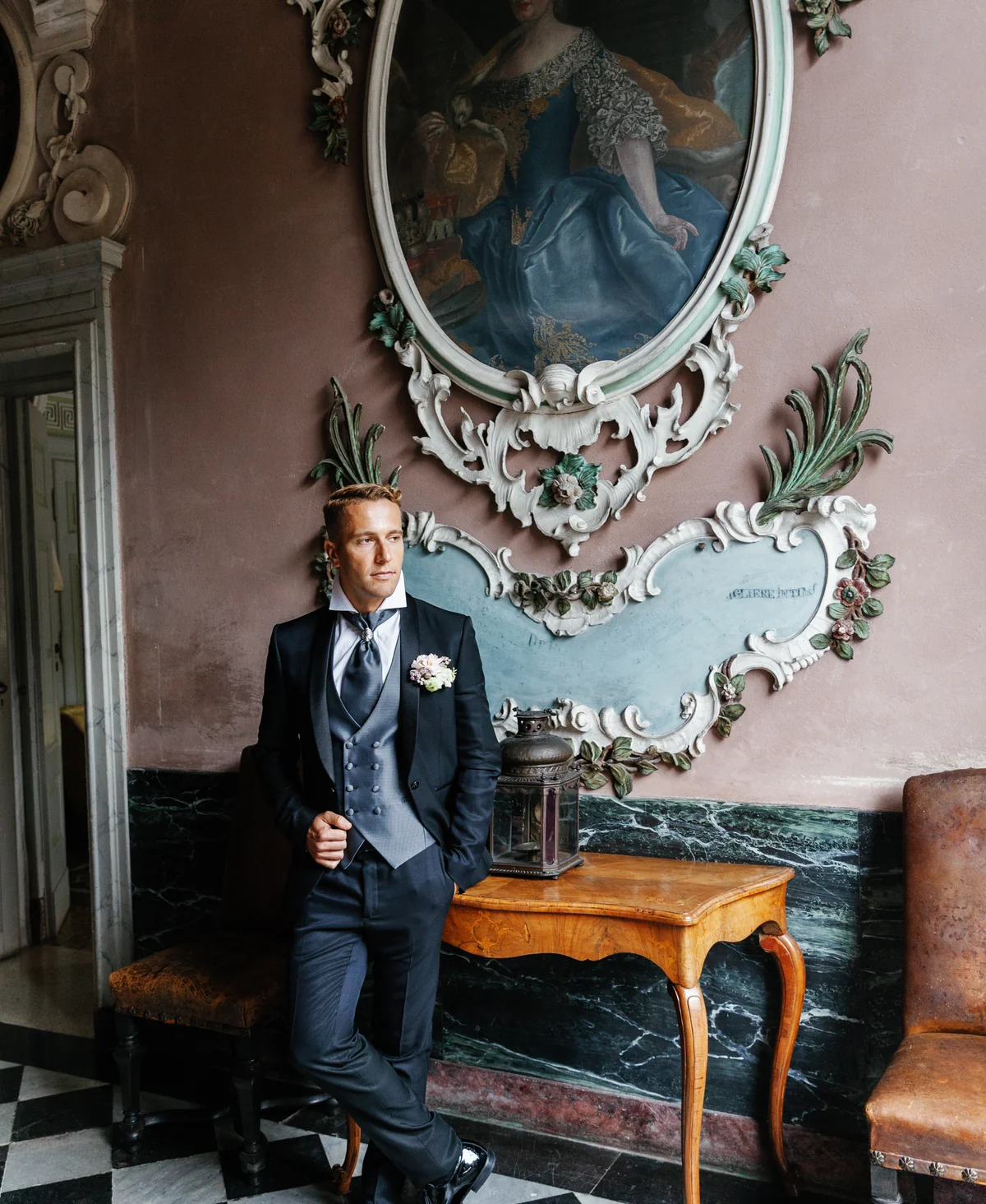 Groom in a tailored suit beneath an antique portrait