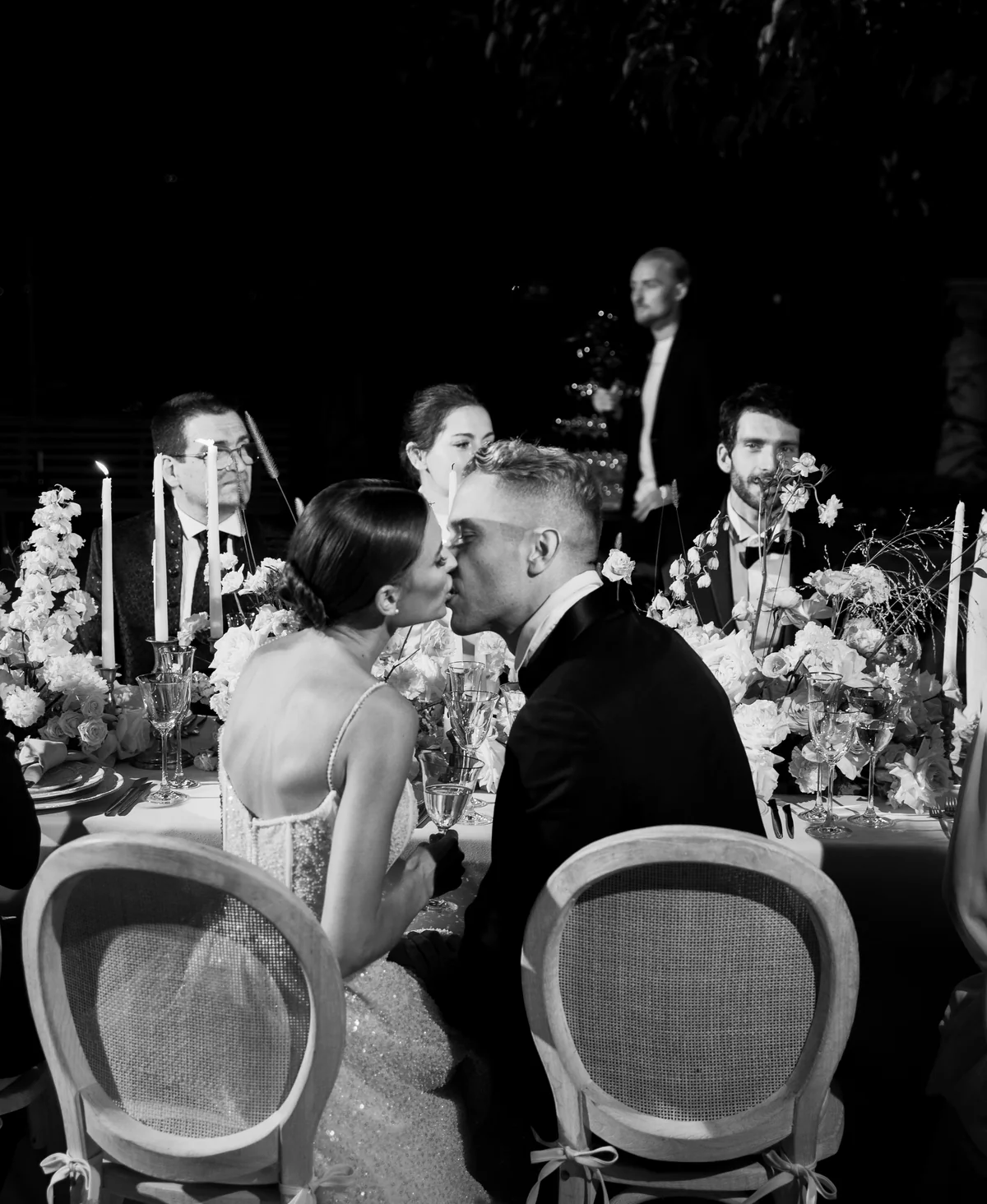 Newlyweds kissing over a candlelit wedding dinner on Lake Como