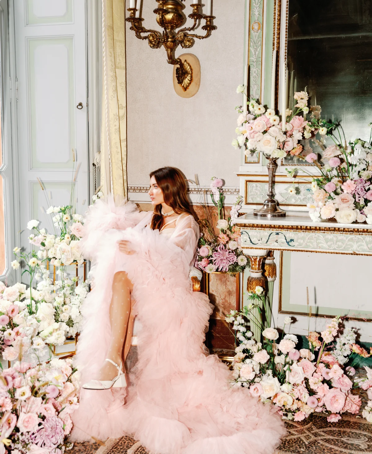 Woman wearing a dramatic pink gown in a flower-filled room