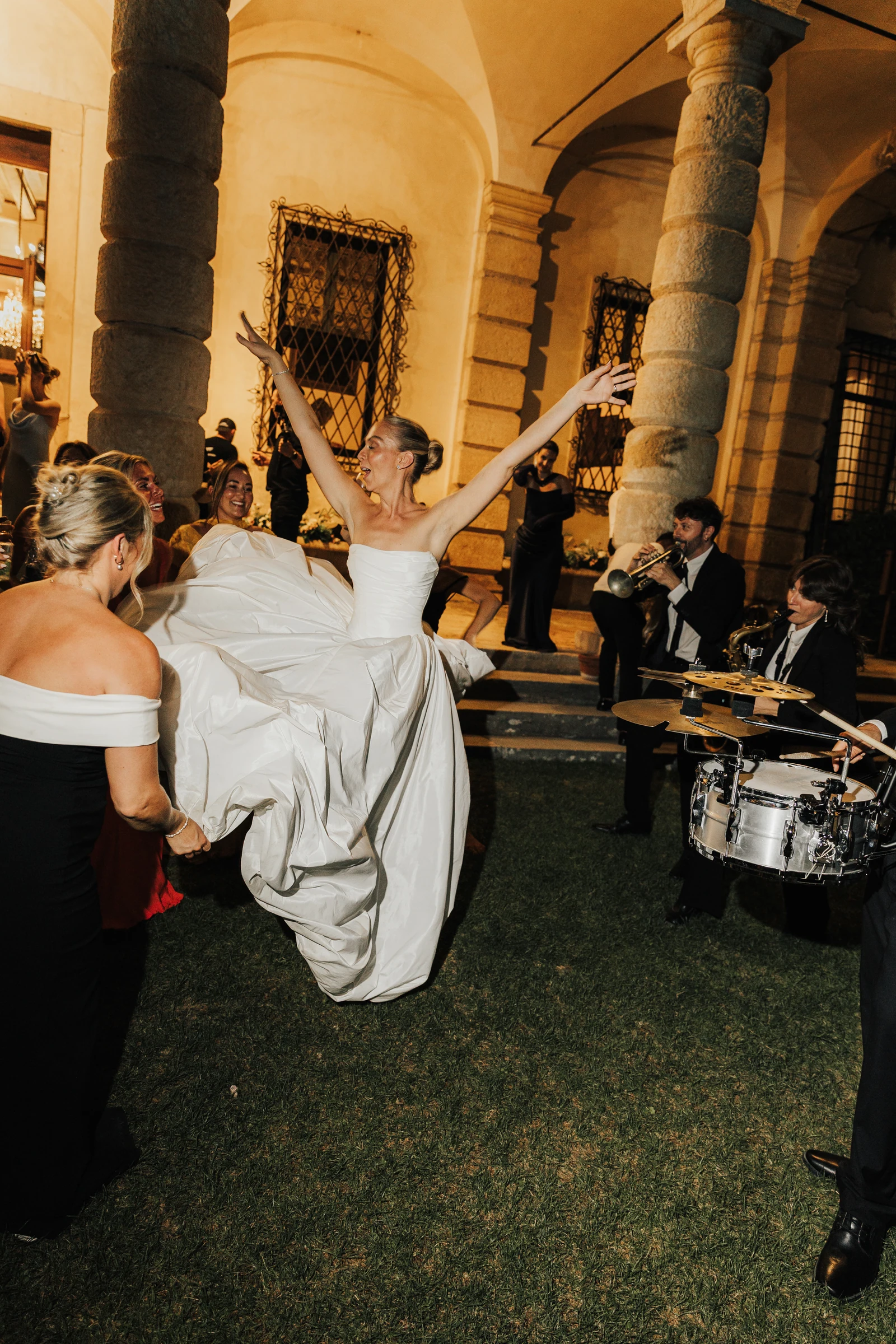 Bride dancing with raised arms beside the live band at Villa Arvedi.