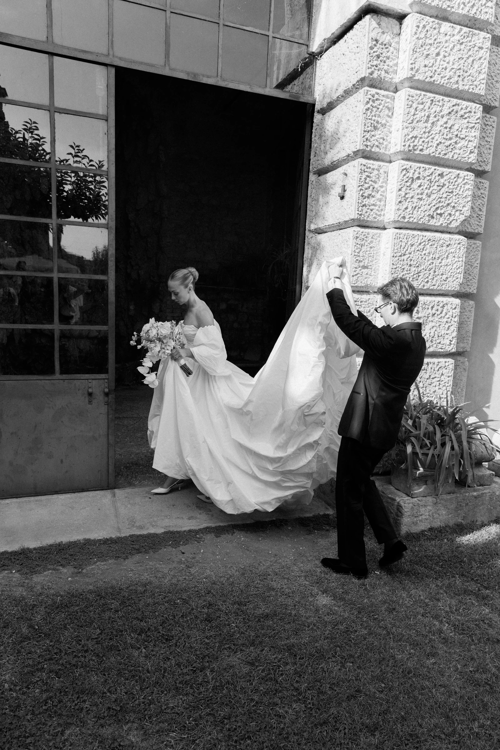 Groom carrying the bride’s train outside Villa Arvedi near Verona.