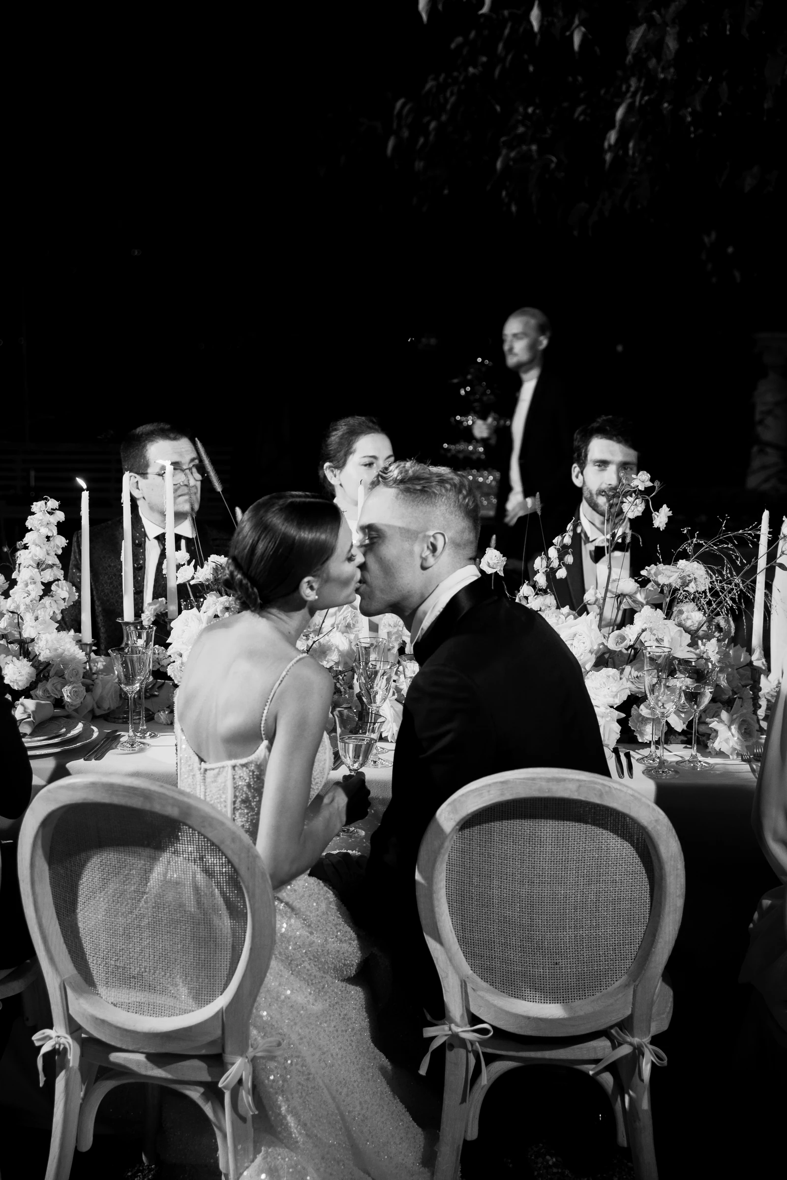 Newlyweds kissing at their candlelit wedding dinner at Villa Pizzo on Lake Como.