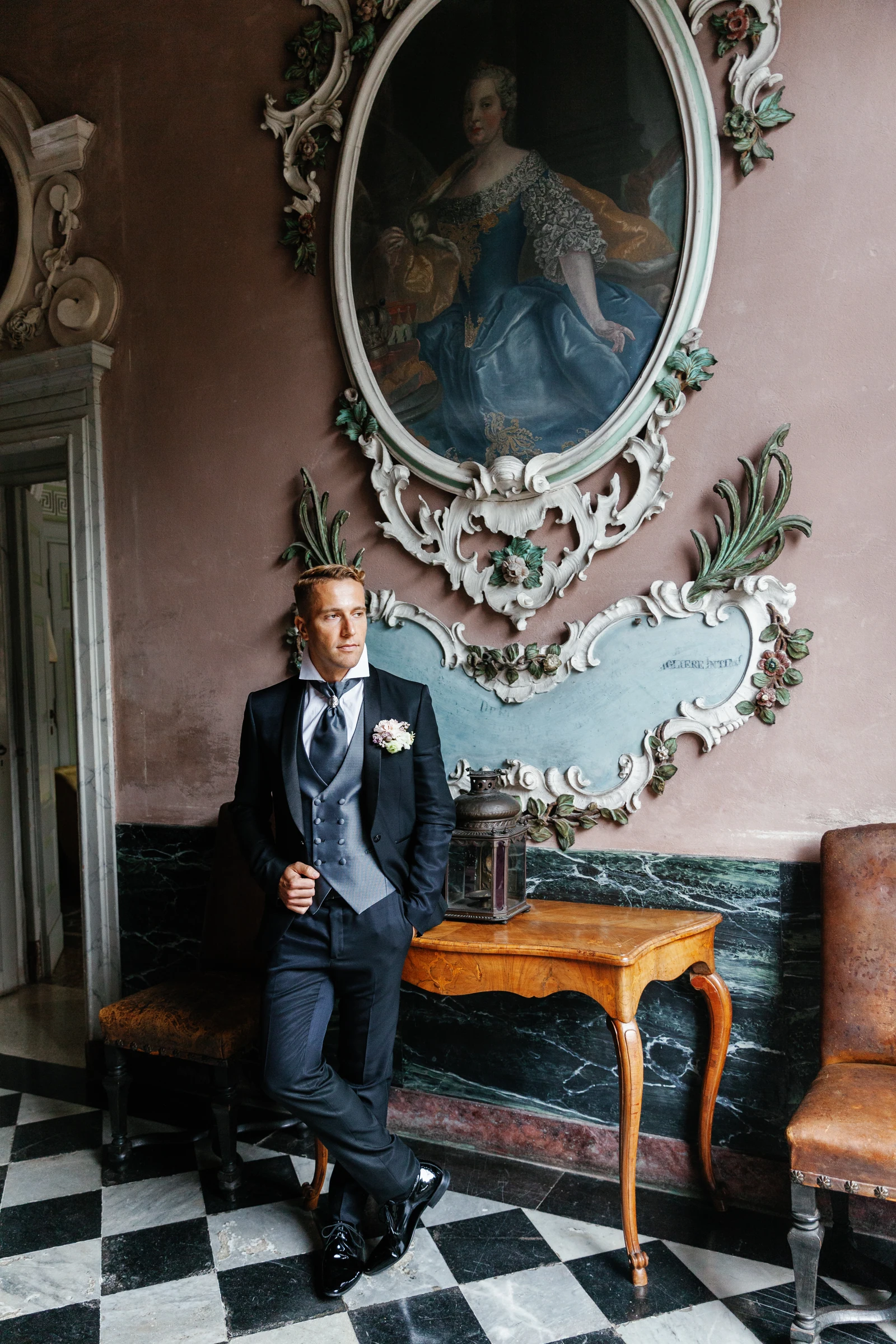 Groom beneath an antique portrait in an ornate room at Villa Pizzo.