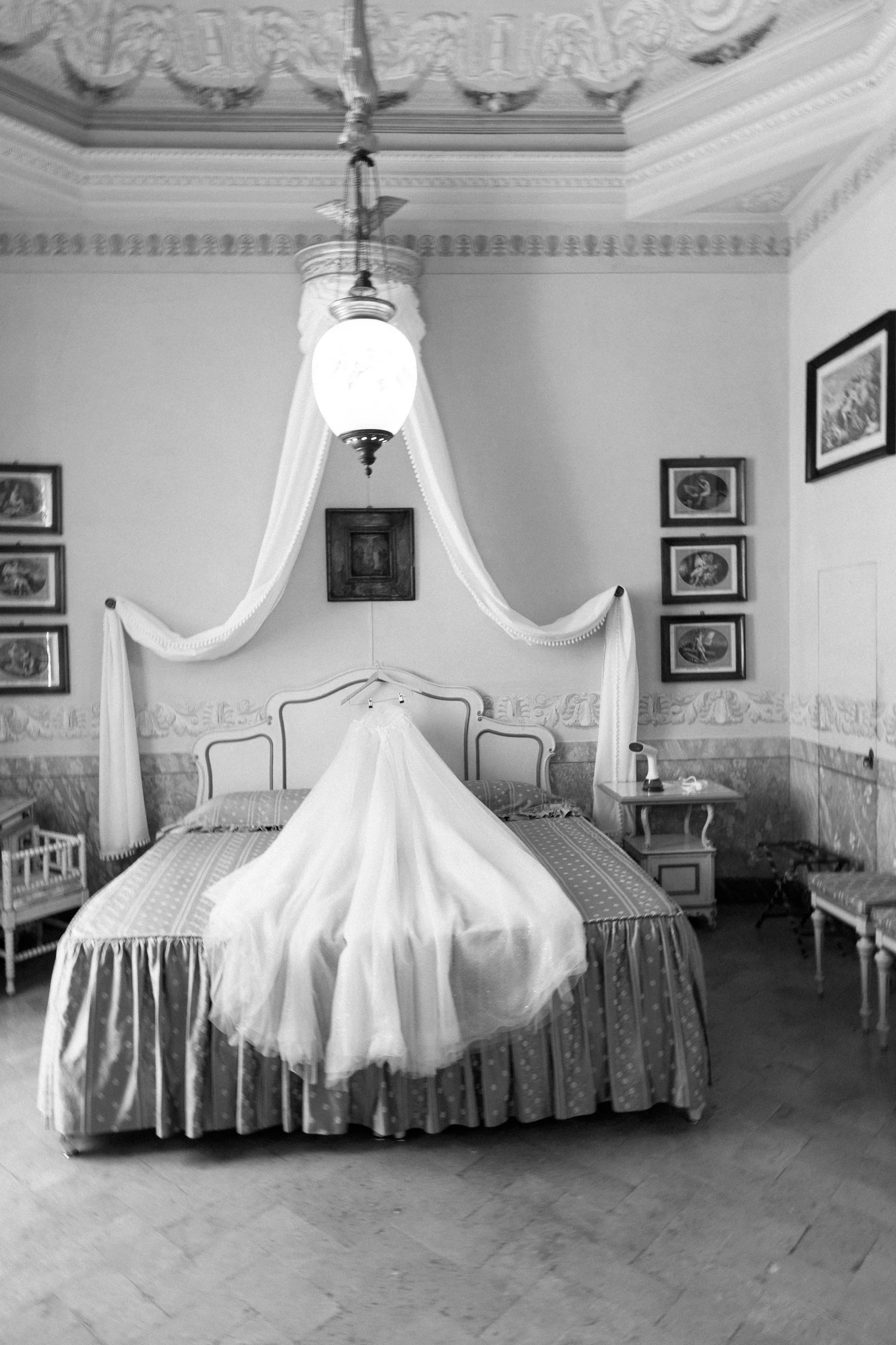 Wedding dress draped over a bed beneath a chandelier at Villa Pizzo.