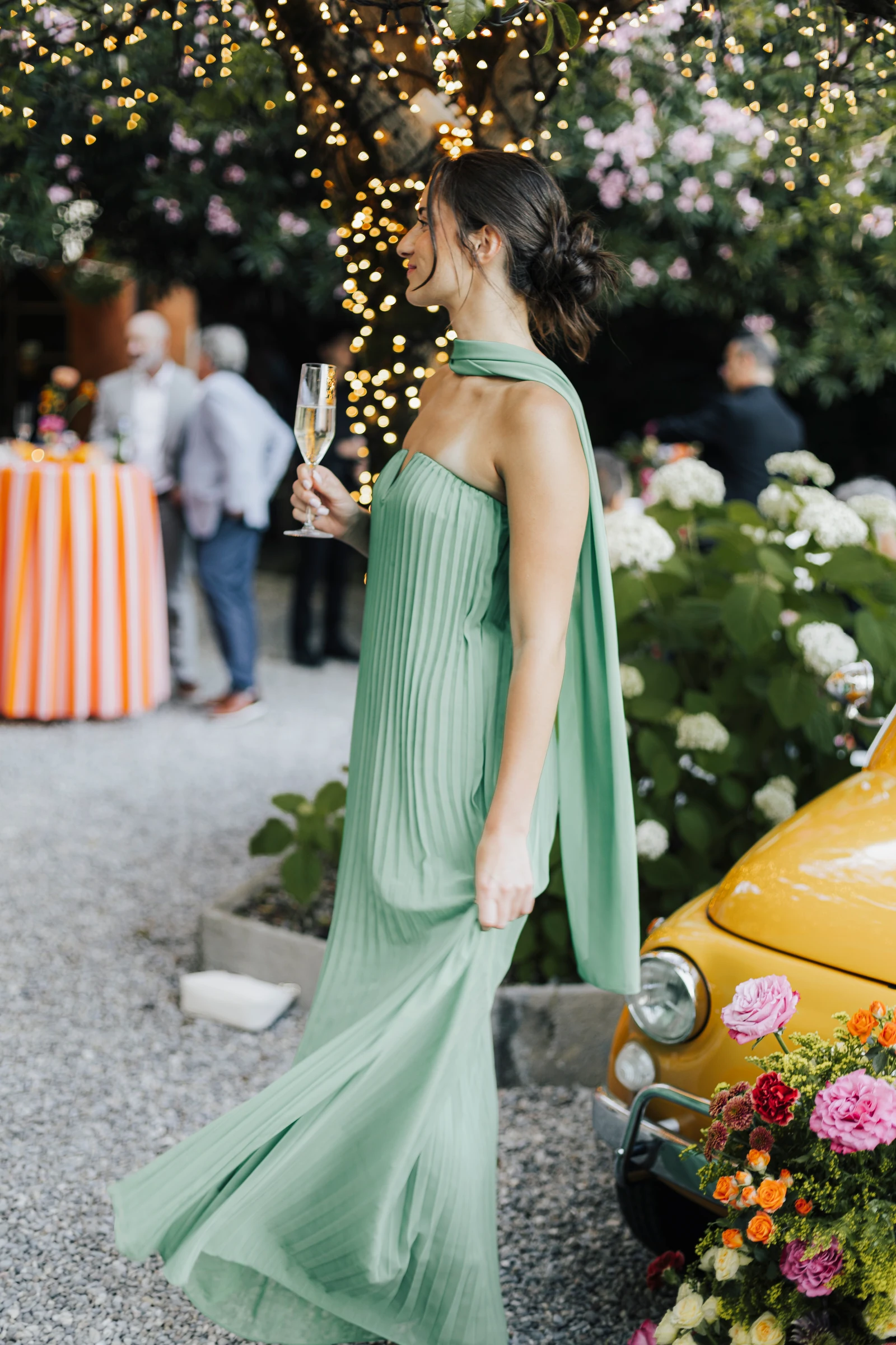 Guest in a flowing green dress beside the yellow Fiat at Villa Regina Teodolinda.