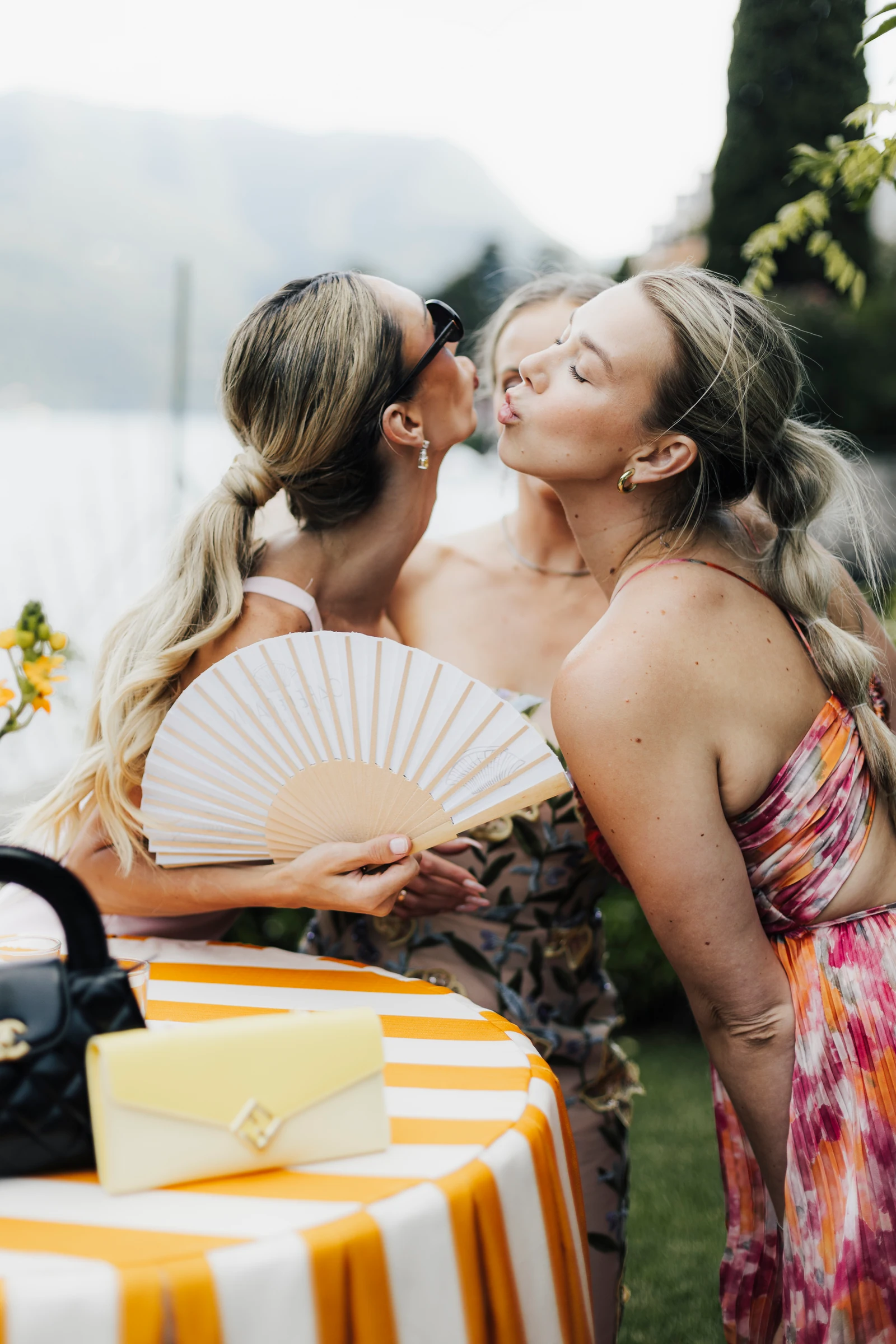 Two guests sharing a cheek kiss beside a striped table at Villa Regina Teodolinda.